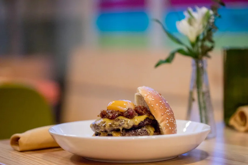 A double cheeseburger with bacon and an egg on top